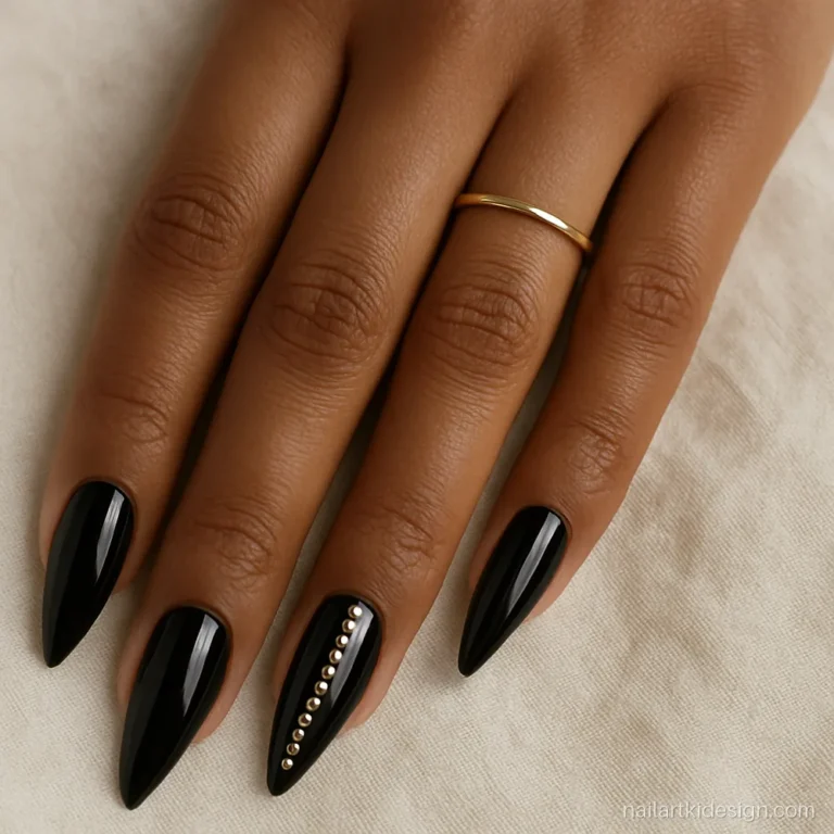 Long stiletto acrylic nails in glossy black with a line of rhinestones