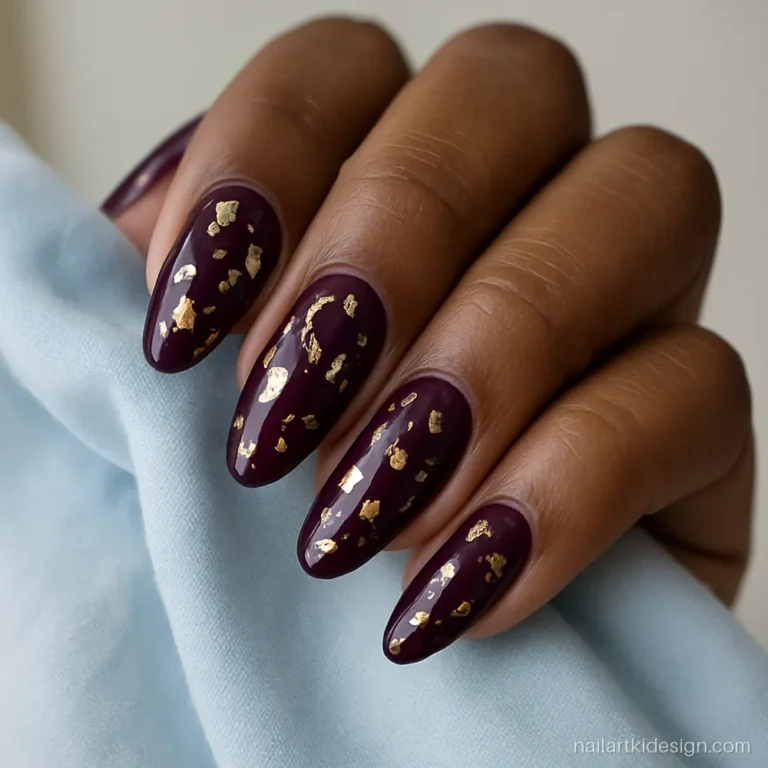 Purple nail art in deep plum with gold foil on long almond nails